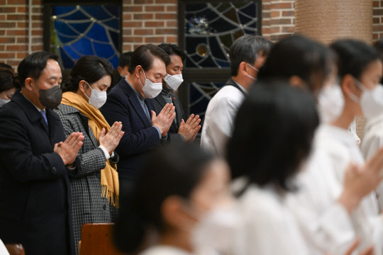 윤석열 대통령과 김건희 여사가 24일 서울 중구 약현성당에서 열린 '주님 성탄 대축일 미사'에 참석해 기도하고 있다.  연합뉴스